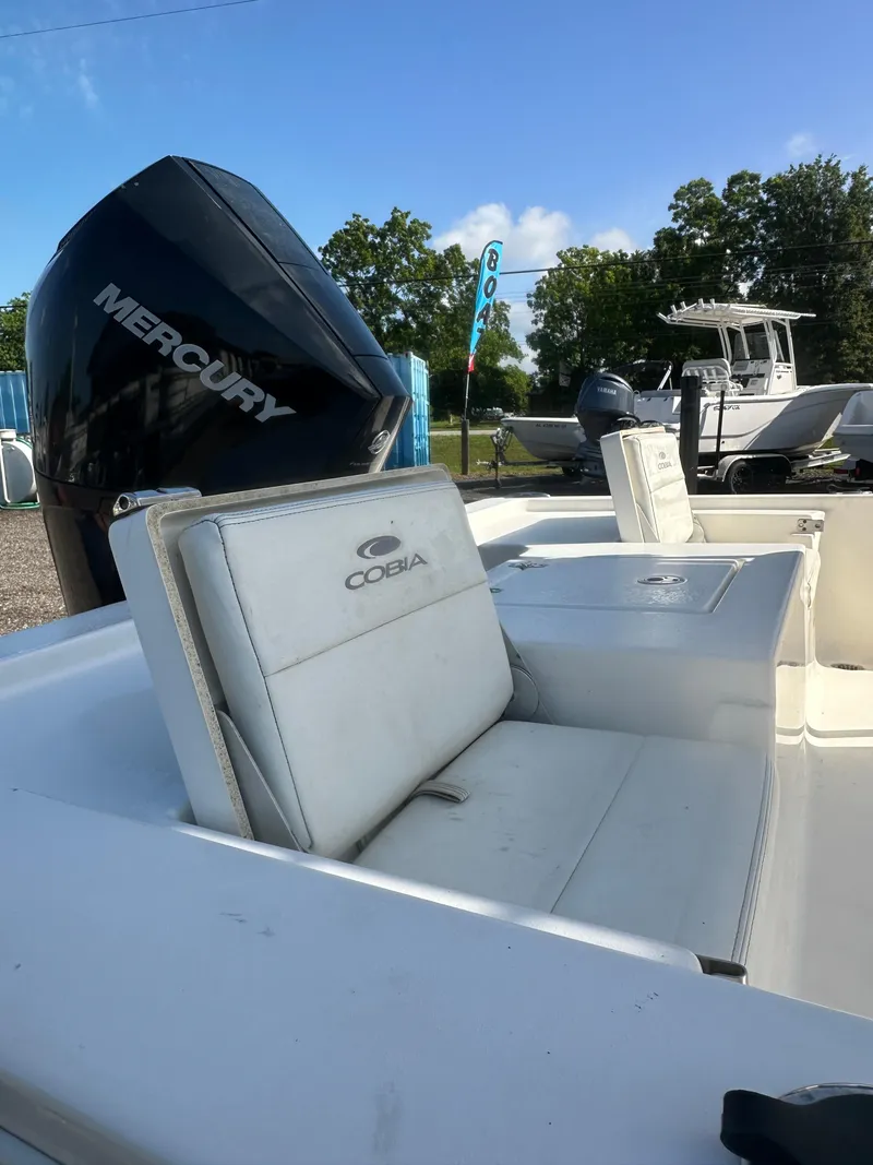 Slide: The Image of 2021 Cobia 21 Bay boat with Mercury engine, featuring white seating and outdoor setting. - 13