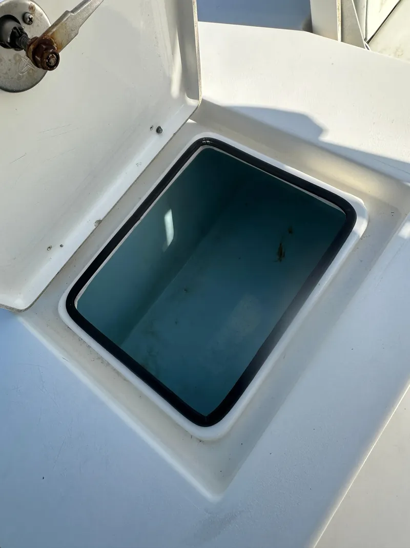 Slide: The Image of 2021 Cobia 21 Bay boat storage compartment with open lid, showcasing interior space. - 17