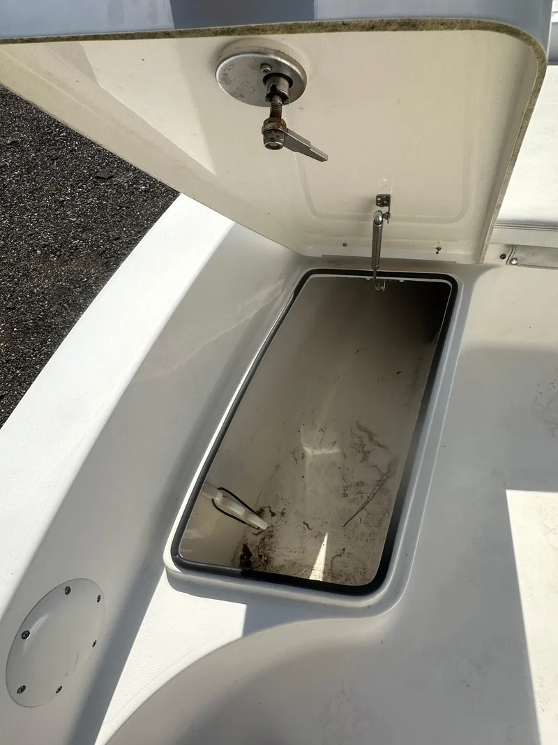 Slide: The Image of 2021 Cobia 21 Bay boat storage compartment with open lid and latch. - 28