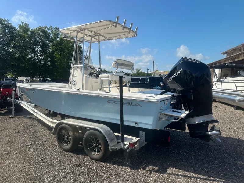 Slide: The Image of 2021 Cobia 21 Bay boat on trailer with Mercury outboard motor, parked outdoors. - 4