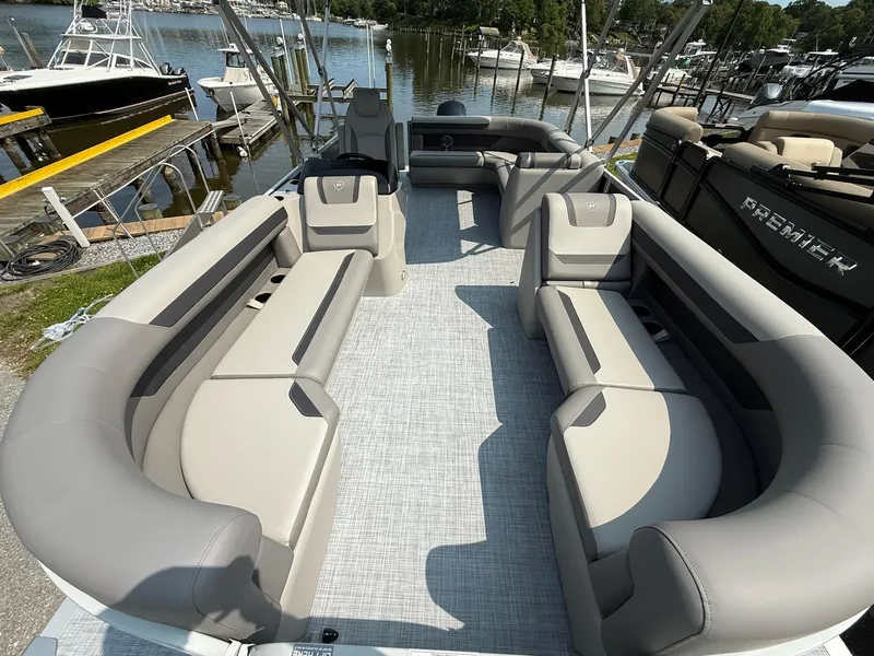 Slide: The Image of 2025 Premier 200 Sunscape RE XLC pontoon boat with spacious seating, docked by the water. - 13