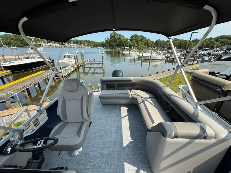 Slide: The Image of 2025 Premier 200 Sunscape RE XLC pontoon boat with spacious seating, docked by a scenic marina. - 5