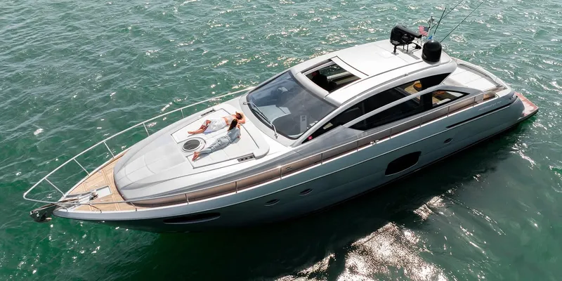 Slide: The Image of 2015 Pershing 62' yacht cruising on clear blue water, featuring sleek design and sunbathing area. - 14