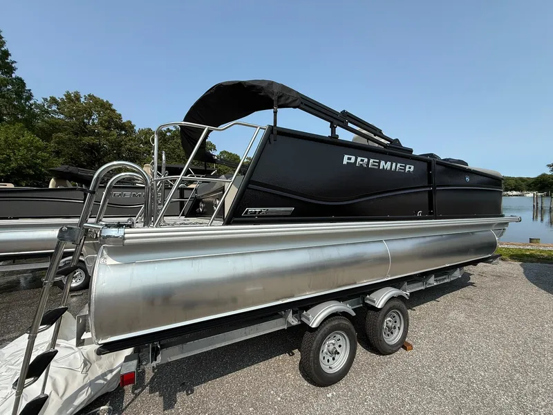 Slide: The Image of 2025 Premier 210 Sunsation RL pontoon boat on trailer, sleek black design, outdoor setting. - 11