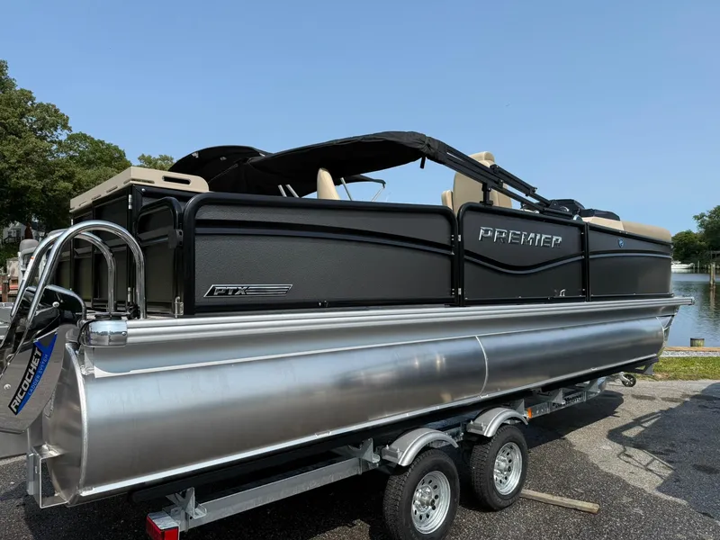 Slide: The Image of 2025 Premier 210 Sunsation RL pontoon boat on trailer, sleek design, lakeside setting. - 17