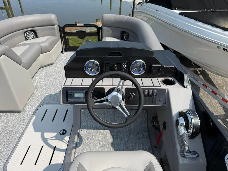Slide: The Image of 2025 Premier 210 Sunsation RL boat interior with steering wheel and seating, docked by the water. - 8