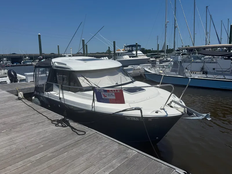 The Image of 2019 Jeanneau NC 695 boat docked, for sale sign visible. - 0