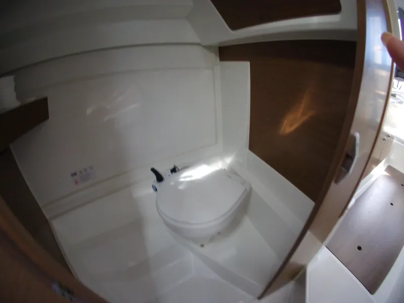 Slide: The Image of 2019 Jeanneau NC 695 boat interior bathroom with compact toilet and wooden accents. - 16
