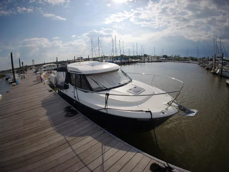 Slide: The Image of 2019 Jeanneau NC 695 boat docked at a marina under a partly cloudy sky. - 2
