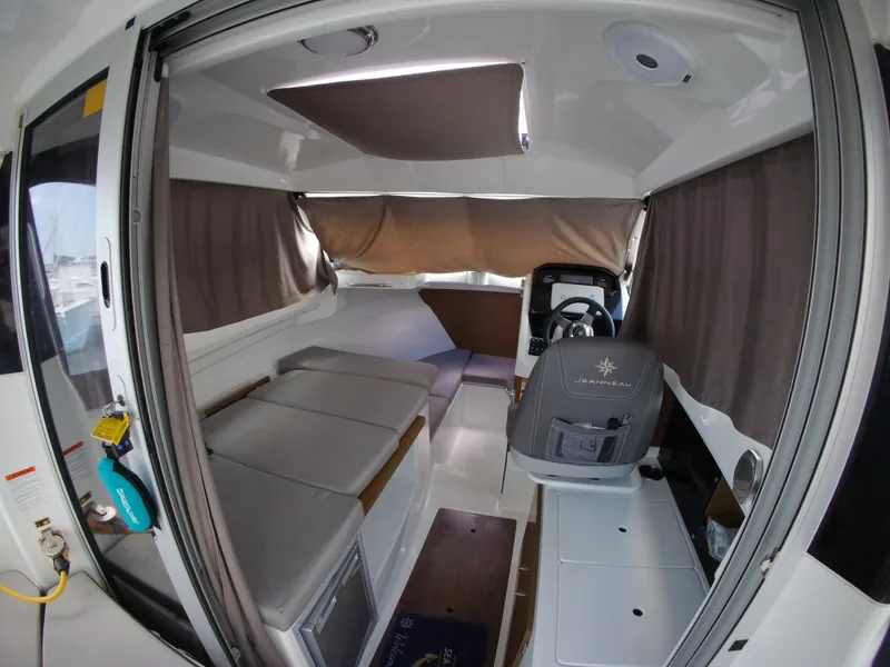 Slide: The Image of 2019 Jeanneau NC 695 interior with seating, helm, and curtains. - 24