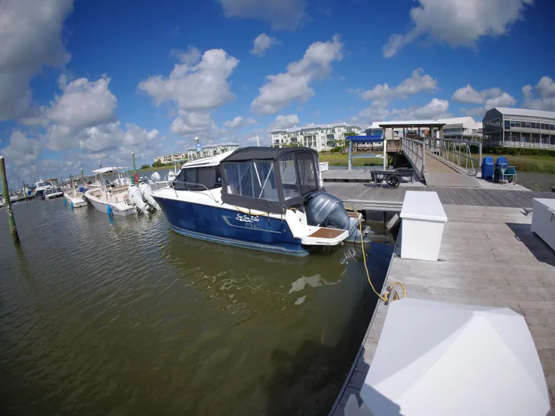 Slide: The Image of 2019 Jeanneau NC 695 boat docked at a marina under a blue sky. - 5