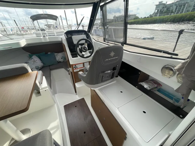 Slide: The Image of 2019 Jeanneau NC 695 boat interior with helm, seating, and storage compartments. - 6