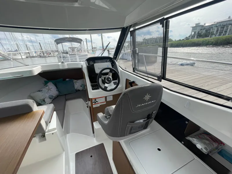 Slide: The Image of 2019 Jeanneau NC 695 boat interior with helm, seating, and large windows. - 7