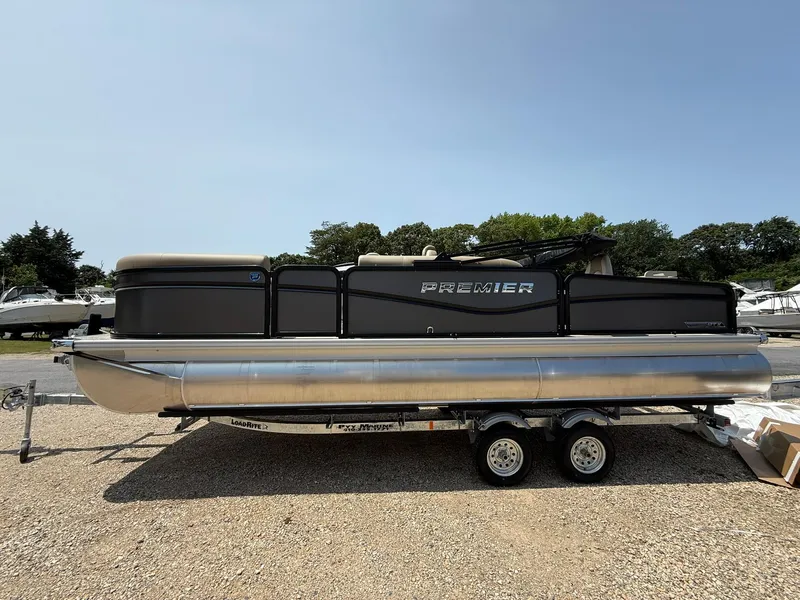 Slide: The Image of 2025 Premier 230 Sunsation Angler 2pt pontoon boat on trailer, parked outdoors. - 22