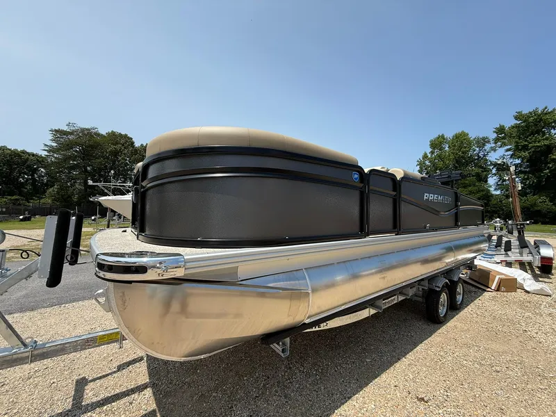 Slide: The Image of 2025 Premier 230 Sunsation Angler 2pt pontoon boat on trailer, parked outdoors. - 23