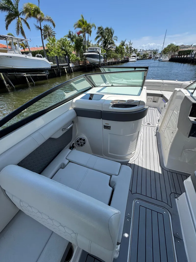 Slide: The Image of 2021 Sea Ray SDX 290 Outboard boat interior with seating, docked by palm trees. - 26