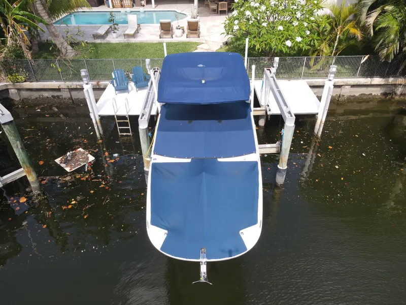 Slide: The Image of 2021 Sea Ray SDX 290 Outboard docked, covered in blue, near a poolside setting. - 35