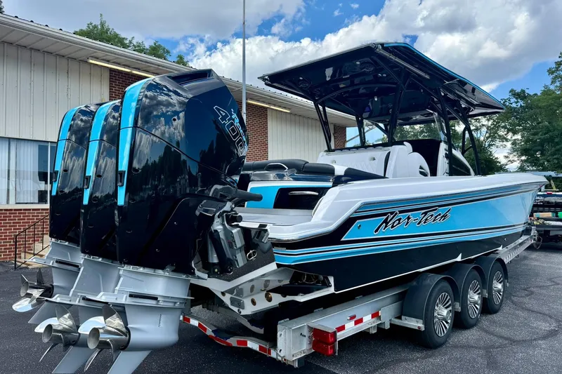 Slide: The Image of 2026 Nor-Tech 340 Sport boat with triple engines on a trailer, parked outdoors. - 4