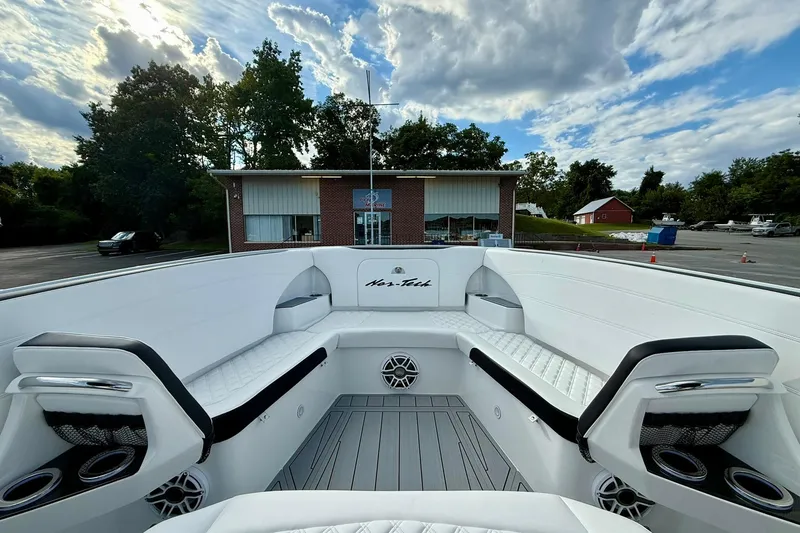 Slide: The Image of 2026 Nor-Tech 340 Sport boat interior with white seating, cup holders, and speakers under a cloudy sky. - 7