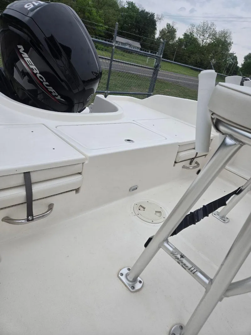 Slide: The Image of 2022 Bayliner Trophy T18Bay boat interior with Mercury engine, white seating, and metal railing. - 7