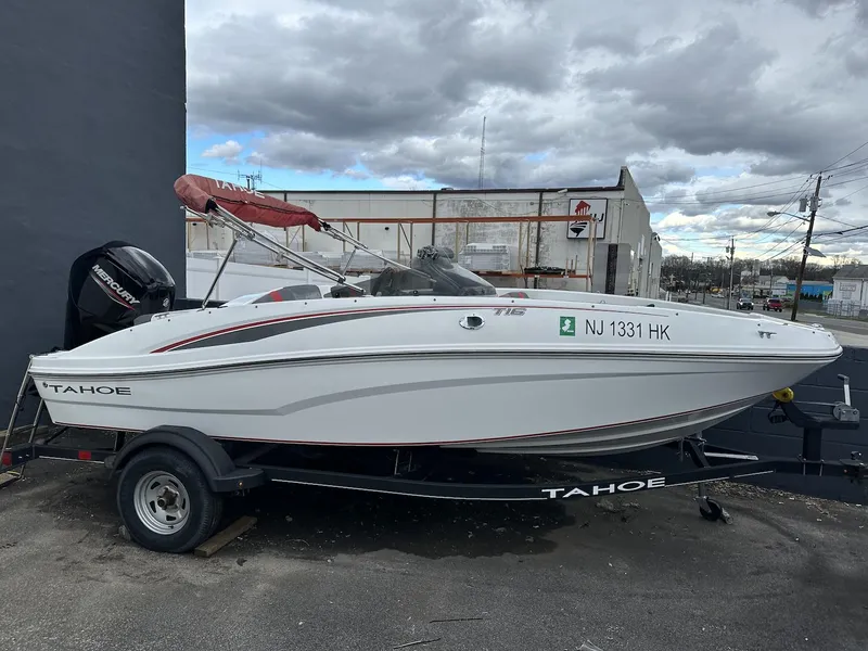 The Image of 2021 Tahoe T16 boat with red canopy on trailer, parked outside dealership. - 0