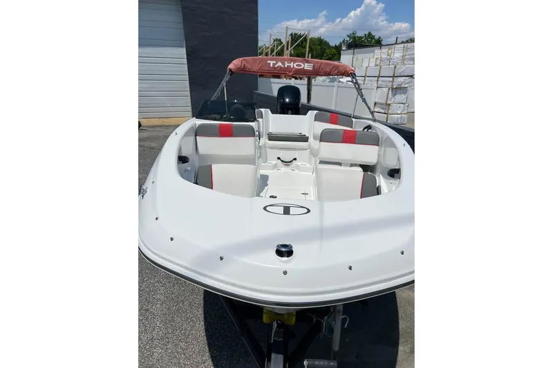 Slide: The Image of 2021 Tahoe T-16 boat on trailer, parked outdoors under cloudy sky. - 2
