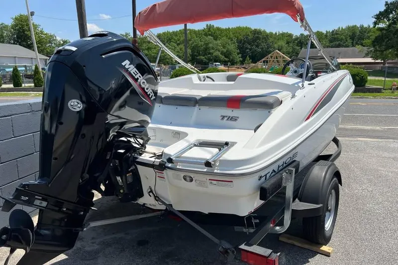 Slide: The Image of 2021 Tahoe T16 boat with red and gray seating, parked outdoors. - 3