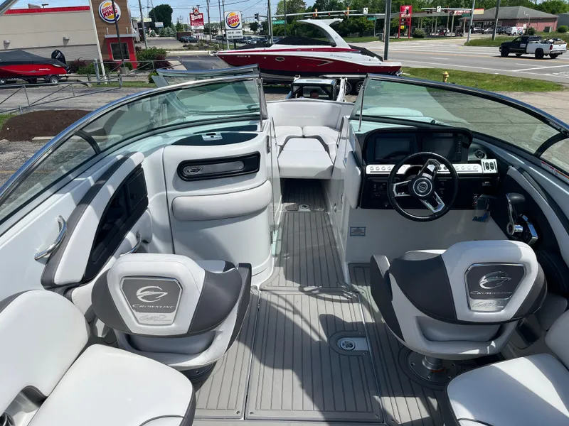 Slide: The Image of 2024 Crownline 270 SS boat interior with modern seating and dashboard, parked near a roadside. - 8