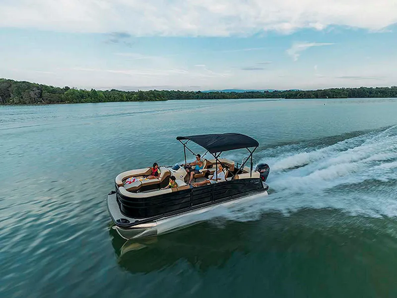 Slide: The Image of 2024 Lowe L-Shaped SS 210 pontoon boat cruising on a serene lake. - 3