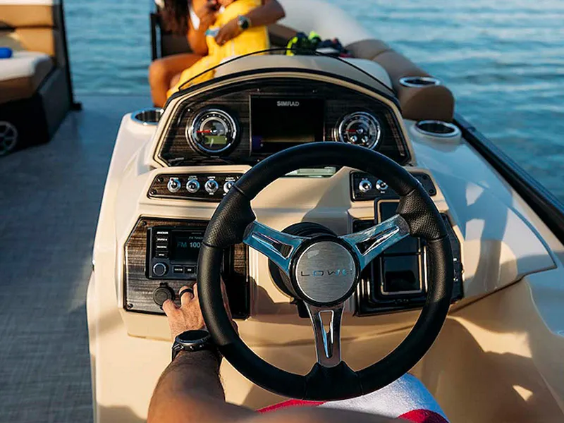 Slide: The Image of 2024 Lowe L-Shaped SS 210 boat dashboard with steering wheel and controls on water. - 8