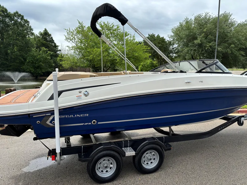 Slide: The Image of 2022 Bayliner VR6 Bowrider I/O on trailer, blue and white design, parked outdoors. - 2
