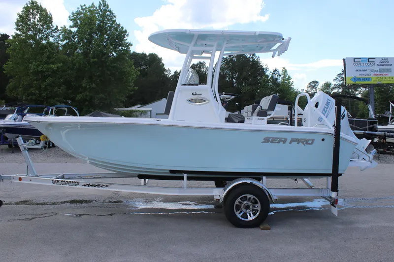 Slide: The Image of 2025 Sea Pro 202 CC boat on trailer, parked outdoors with trees in background. - 3