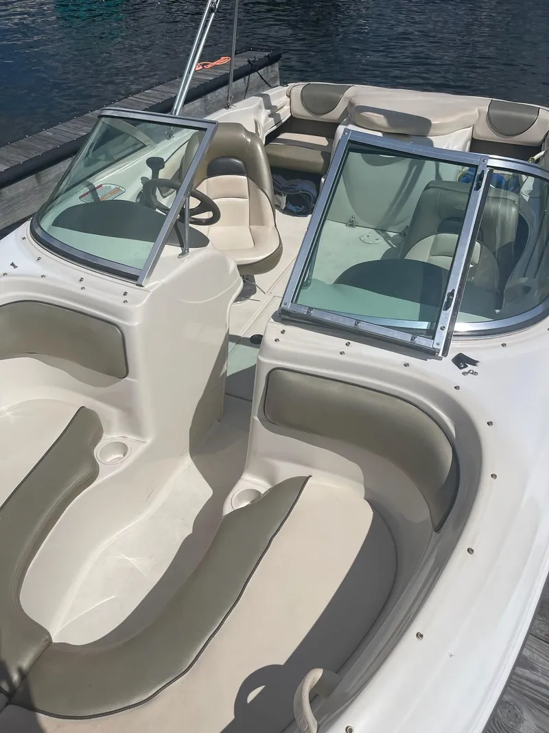 Slide: The Image of 2004 Sea Ray 185 Bow Rider boat with beige interior, docked on calm water. - 13
