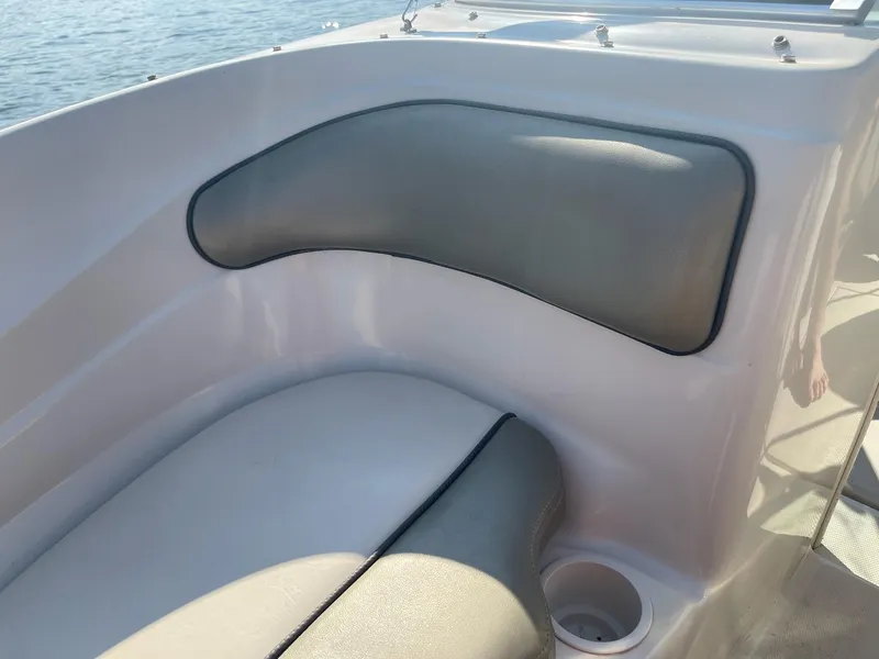 Slide: The Image of 2004 Sea Ray 185 Bow Rider interior seating with cup holder, on calm water. - 14