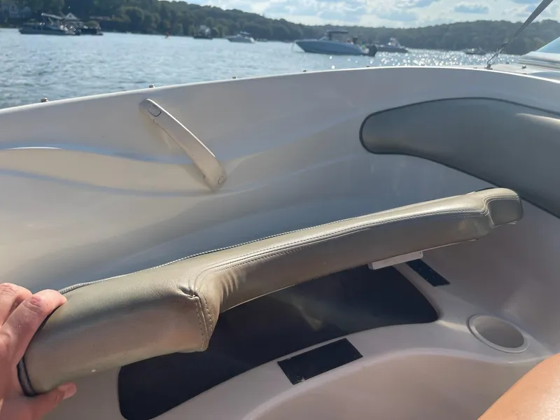 Slide: The Image of 2004 Sea Ray 185 Bow Rider interior with cushioned seating on a sunny day. - 15