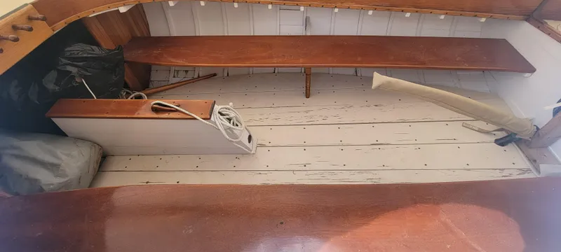 Slide: The Image of Interior of a 1916 Herreshoff Buzzards Bay 15 sailboat with wooden benches and flooring. - 4