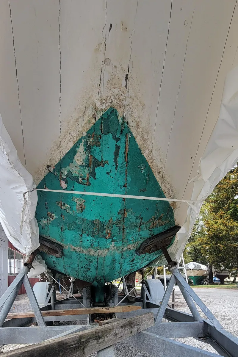 Slide: The Image of 1916 Herreshoff Buzzards Bay 15 sailboat under restoration, showing weathered hull and support structure. - 9