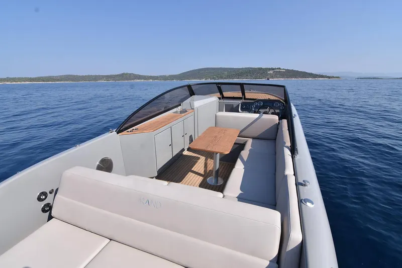 Slide: The Image of 2025 Rand Supreme 27 boat with sleek design, spacious seating, and wooden table on calm waters. - 22