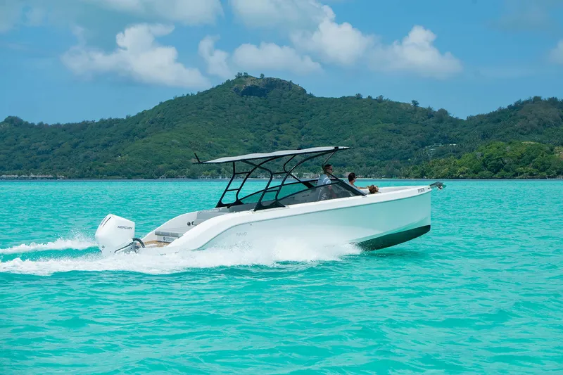 Slide: The Image of 2025 Rand Supreme 27 boat cruising on turquoise water with lush green hills in the background. - 24