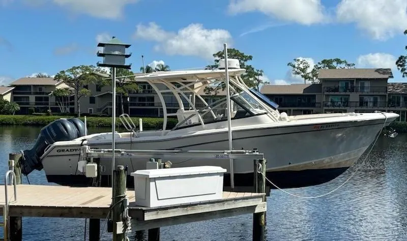 Slide: The Image of 2016 Grady-White Freedom 275 boat docked on a sunny day, surrounded by water and buildings. - 0