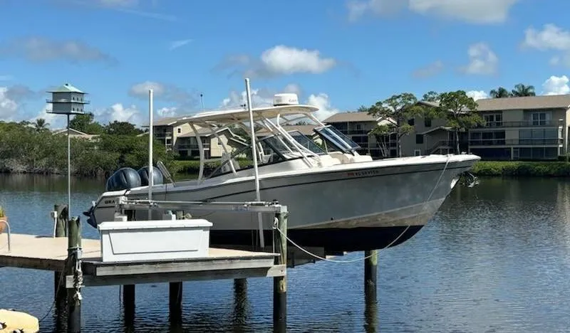 Slide: The Image of 2016 Grady-White Freedom 275 boat docked on a serene lake with clear skies. - 1