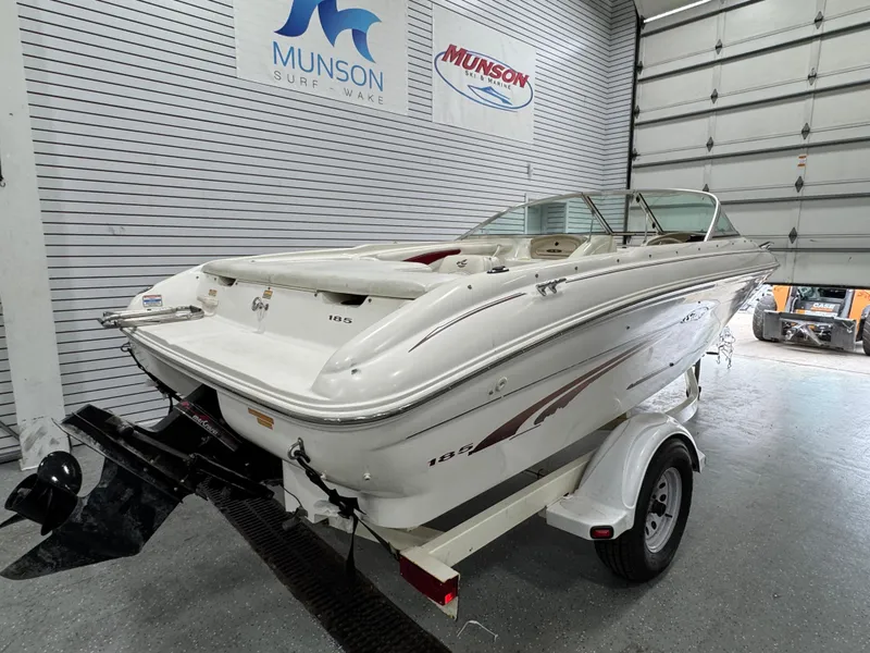 Slide: The Image of 1997 Sea Ray 185 BR boat on trailer in showroom, Munson Surf & Wake signage visible. - 4