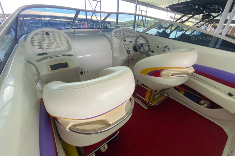 Slide: The Image of Interior of a 1997 Baja 302 Boss boat with white seats and colorful accents. - 10