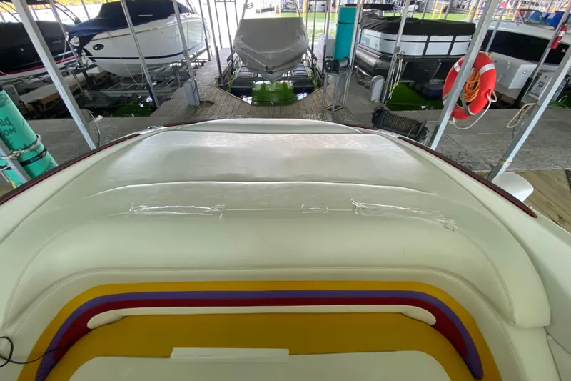 Slide: The Image of 1997 Baja 302 Boss boat interior with colorful seating in a marina. - 16