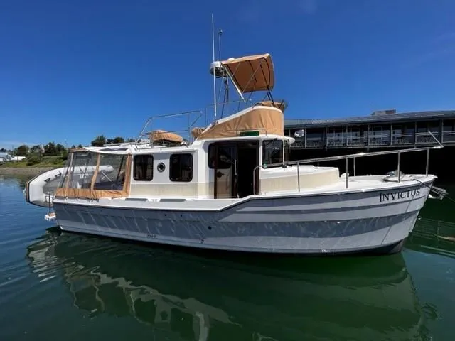 Slide: The Image of 2022 Ranger Tugs R-31 CB boat docked on calm water under clear blue sky. - 0