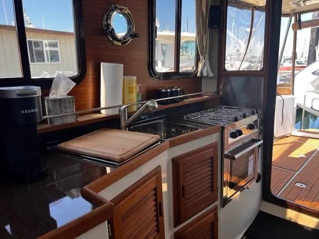 Slide: The Image of Interior of 2022 Ranger Tugs R-31 CB boat, featuring a compact kitchen with stove and sink. - 12