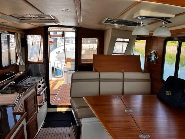 Slide: The Image of Interior of 2022 Ranger Tugs R-31 CB, featuring dining area and kitchen with wood accents. - 16