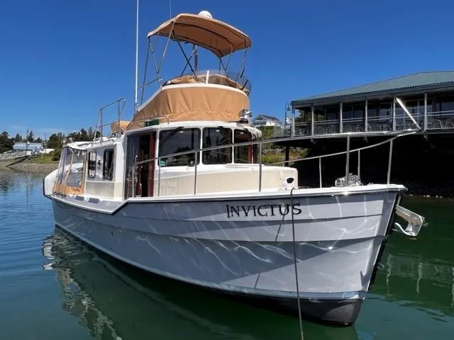 Slide: The Image of 2022 Ranger Tugs R-31 CB boat named "Invictus" docked in a marina. - 2