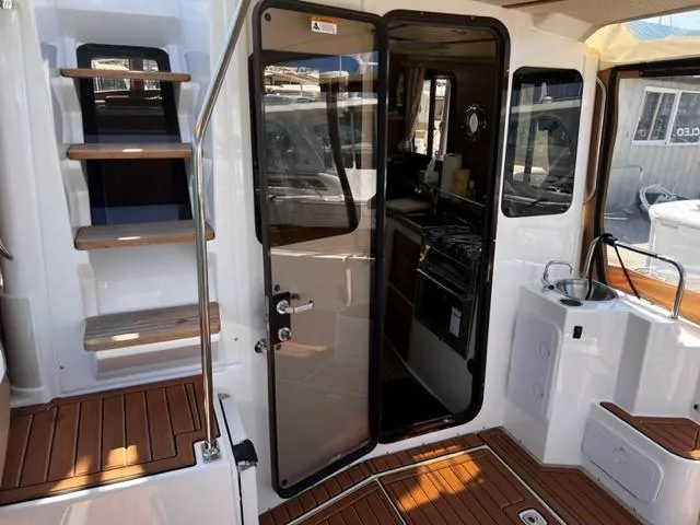 Slide: The Image of 2022 Ranger Tugs R-31 CB interior with wooden steps, glass door, and compact kitchen area. - 9
