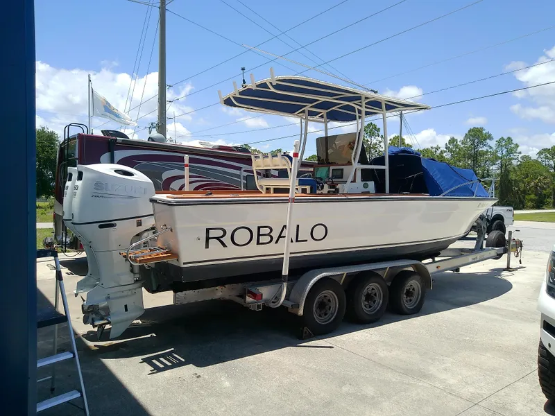 Slide: The Image of 1985 Robalo 2520 Center Console boat on trailer, parked outdoors under clear sky. - 11